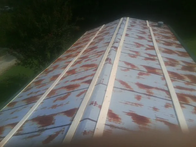 Rusted metal roof panels with new wood purlins before replacement — Storm Damage Roof Repair in Luck by Roofing Brothers