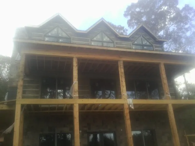 Dormers and porch framing on a large log home under construction — Roof Coating work by our crew in Luck