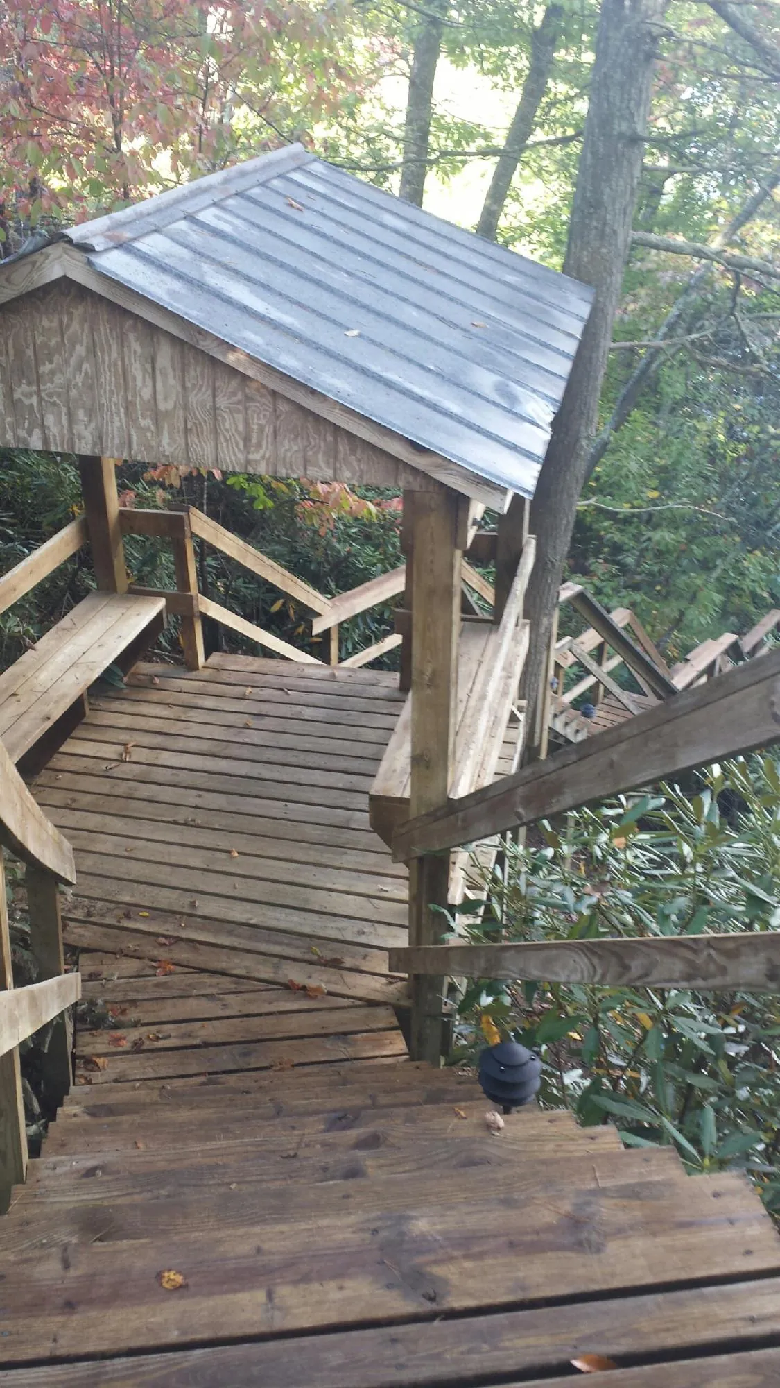 Metal roofed shelter over wooden steps on a wooded walkway — Skylight Repair & Installation work by our crew in Luck